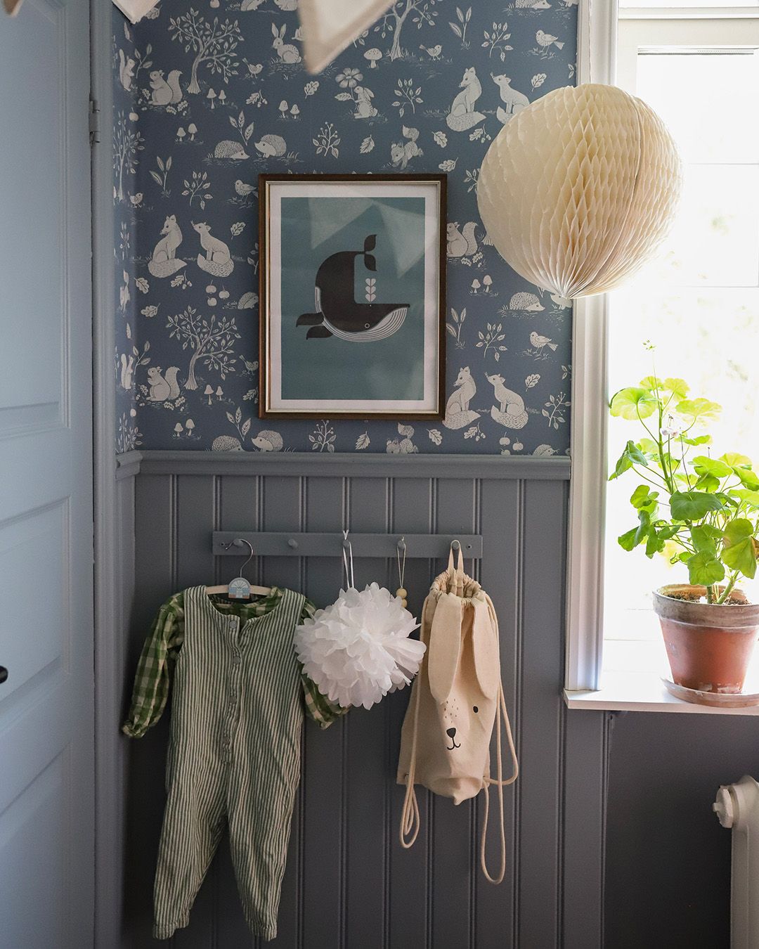 fint barnrum med blå tapet och pärlspont. inmålad dörr med speglar och kroklist.
