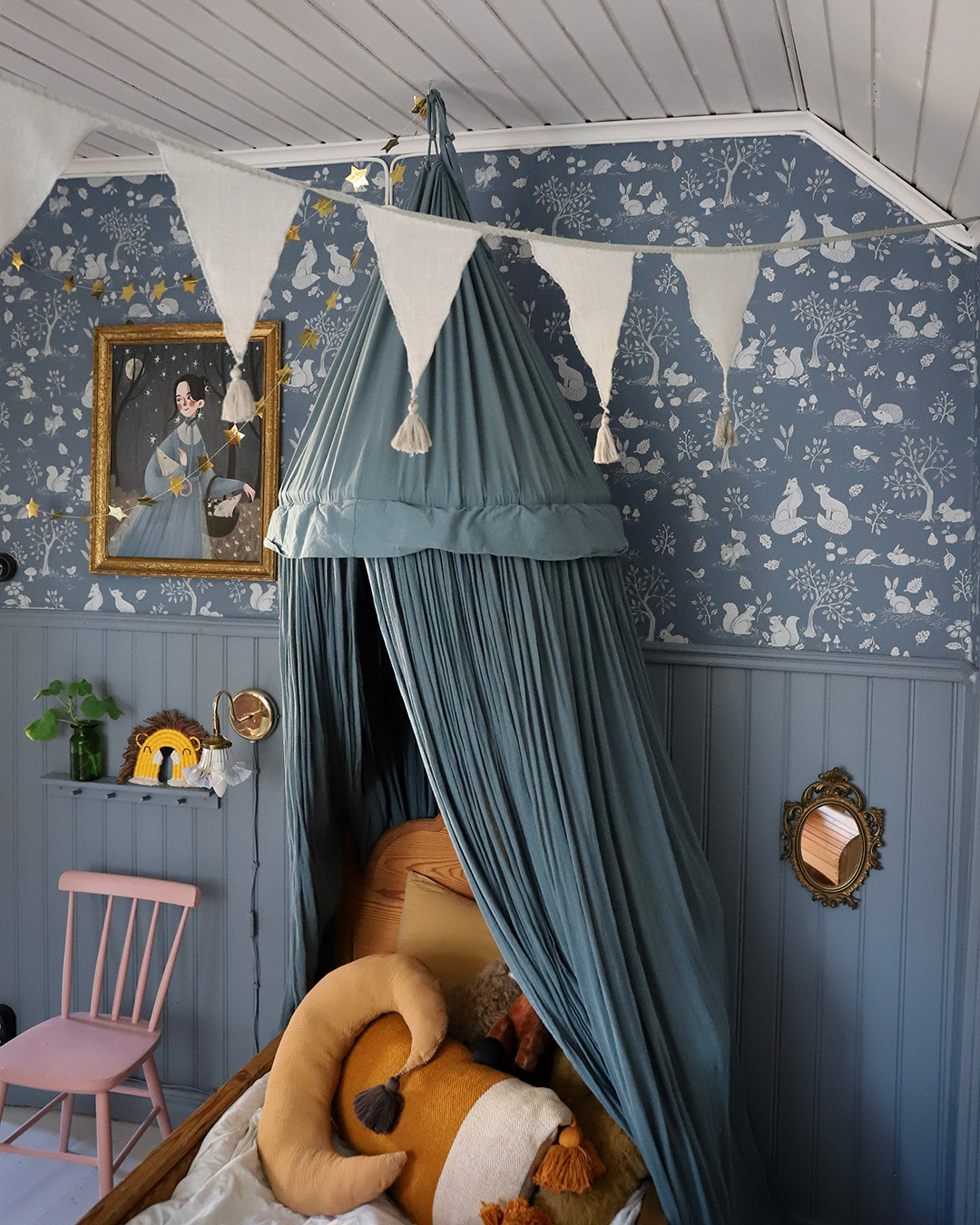 blå barntapet med söta små djur som möts av blå pärlspont. Blå sänghimmel med vita vimplar i taket.