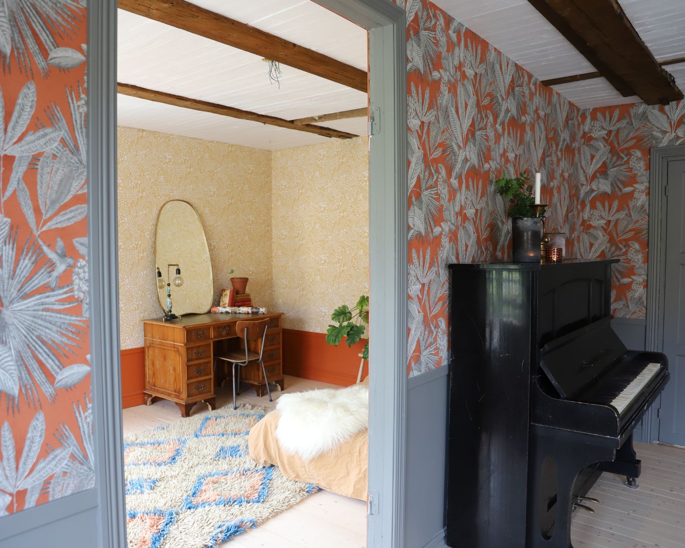 arbetsrum med gul tapet som skymtar genom dörröppning från rum med stormönstrad tapet