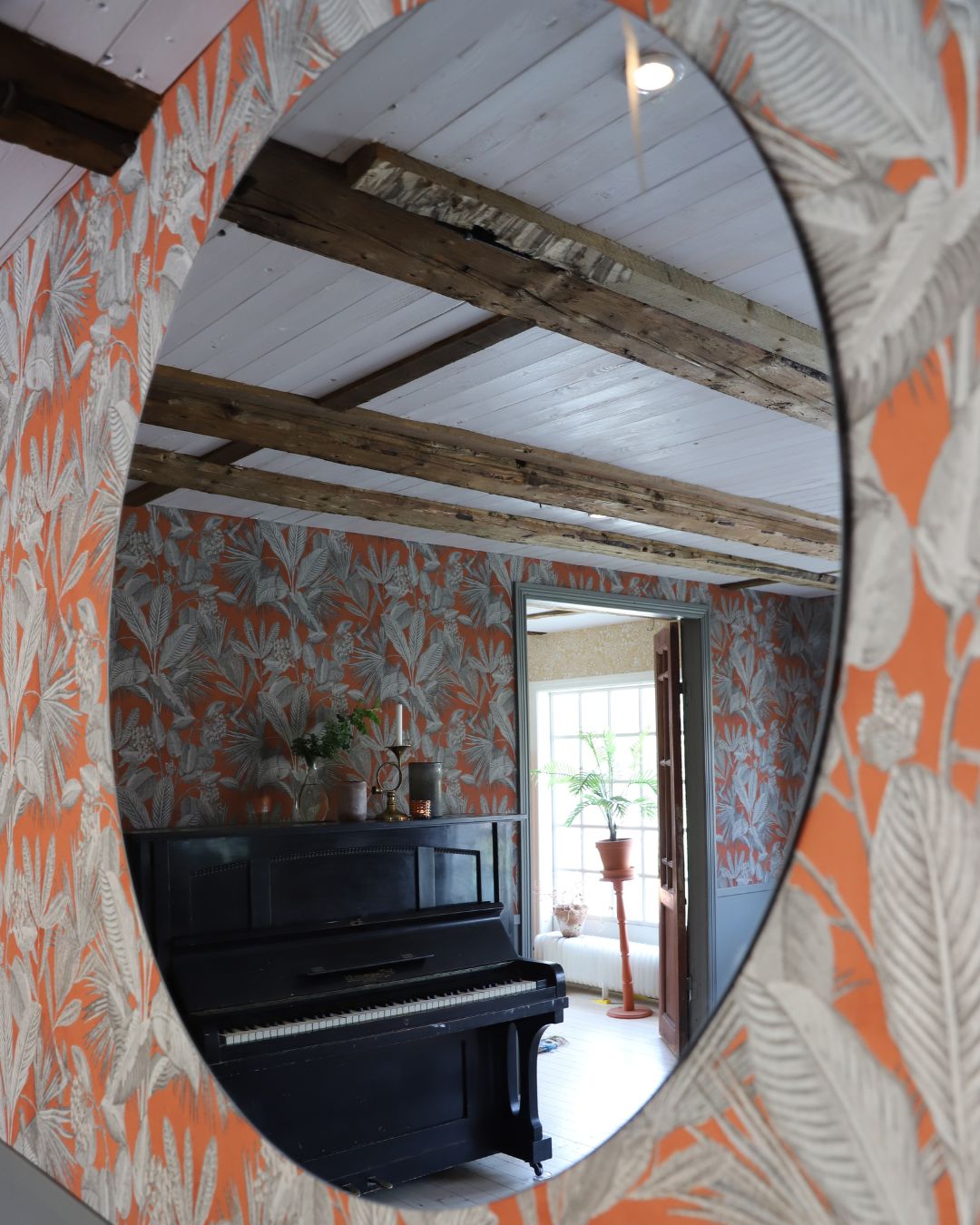 vardagsrum med orange tapet med bladmönster som möter grå panel
