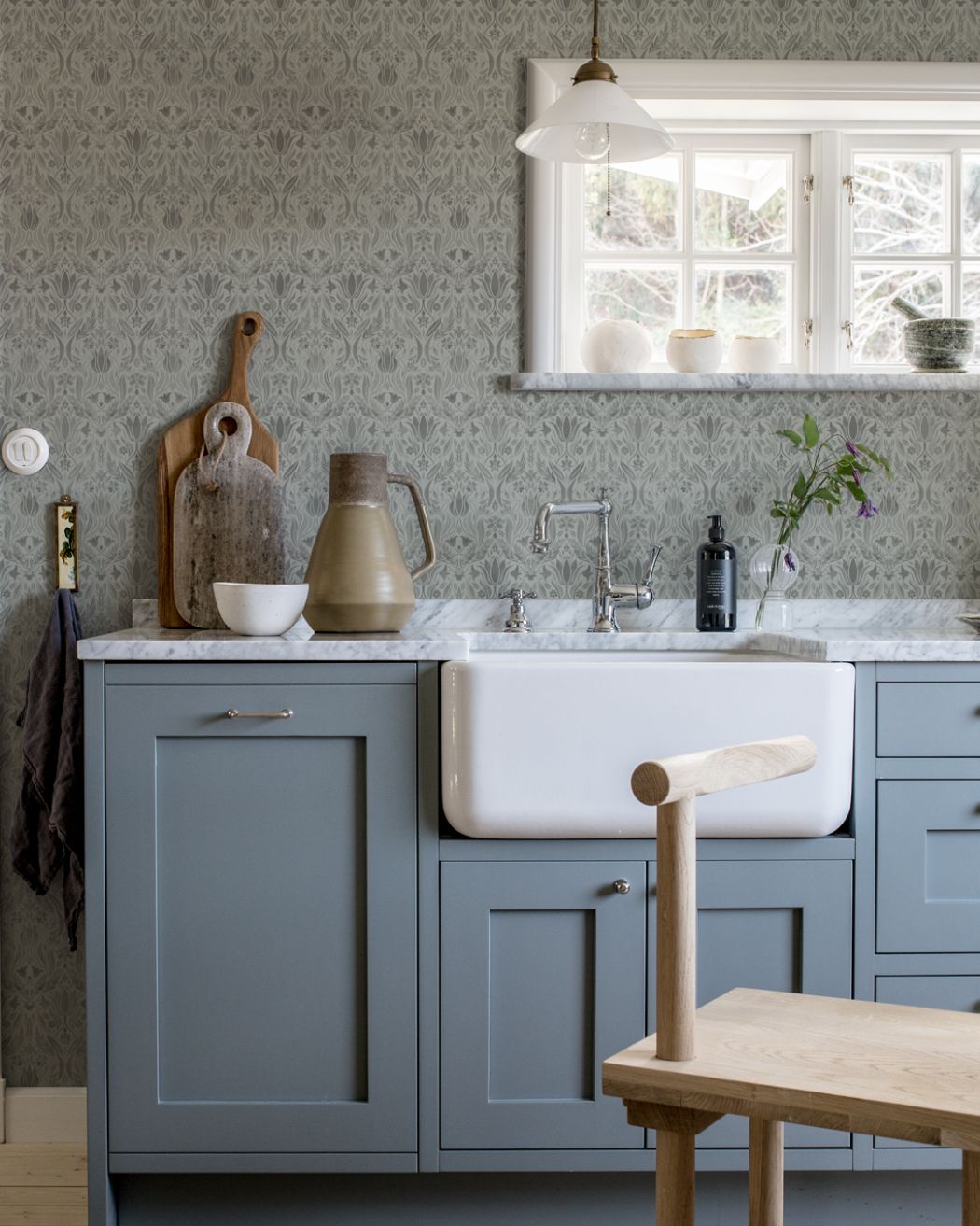 grå tapet i lantligt kök som går ton i ton grå och mörkgrå. Bänkskiva i marmor och djup sink.