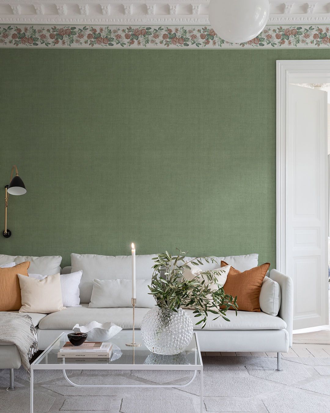 vardagsrum med grön tapet och blommig bård längs med taket